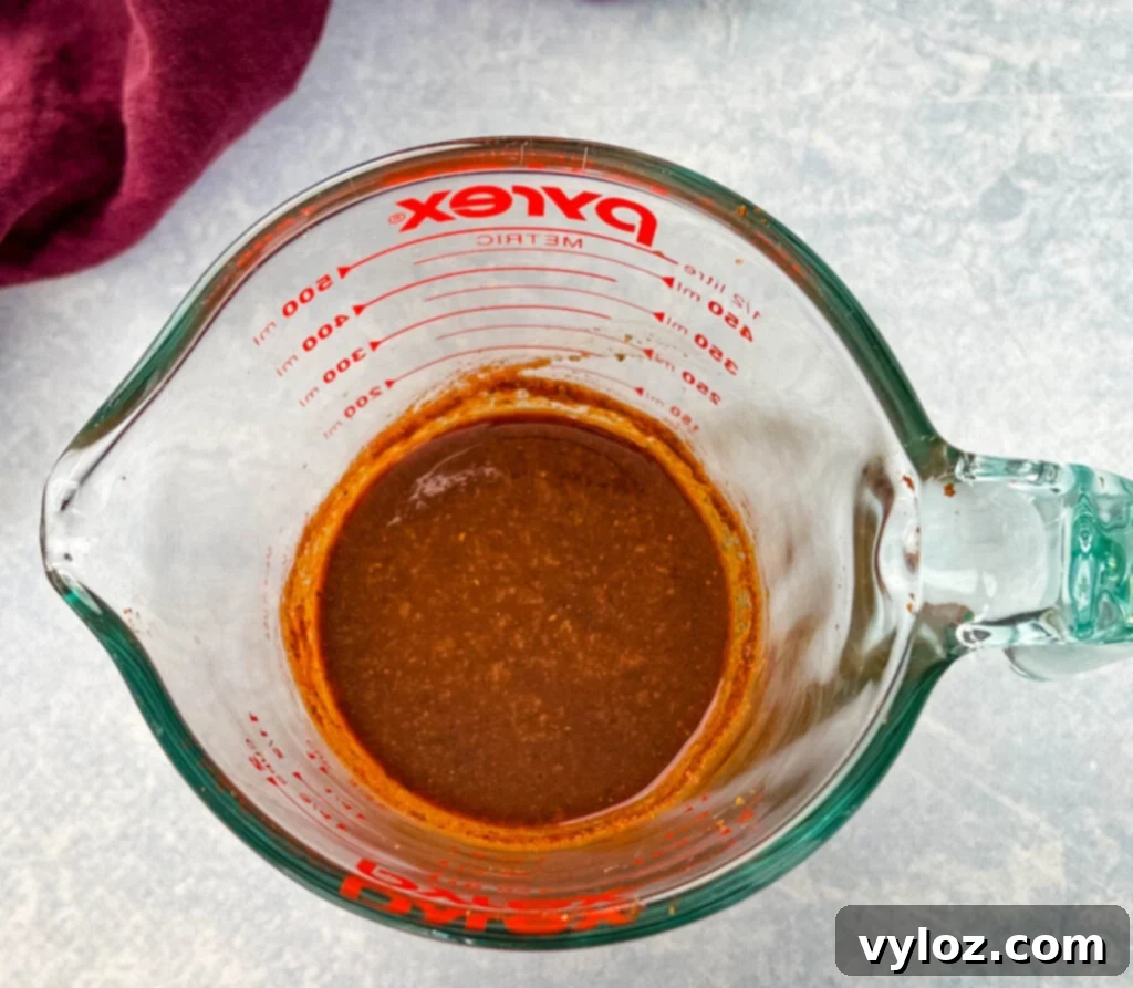 Bold Caribbean Jerk Marinade 2 Rich, vibrant homemade jerk marinade in a clear glass measuring cup, ready to infuse chicken with authentic Caribbean flavor.