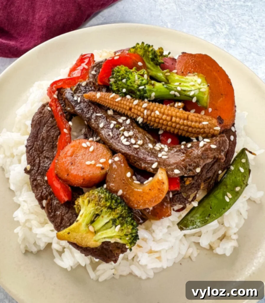 Sizzling Teriyaki Beef 7 Delicious beef stir fry with mixed vegetables served over a bed of white rice, garnished with sesame seeds