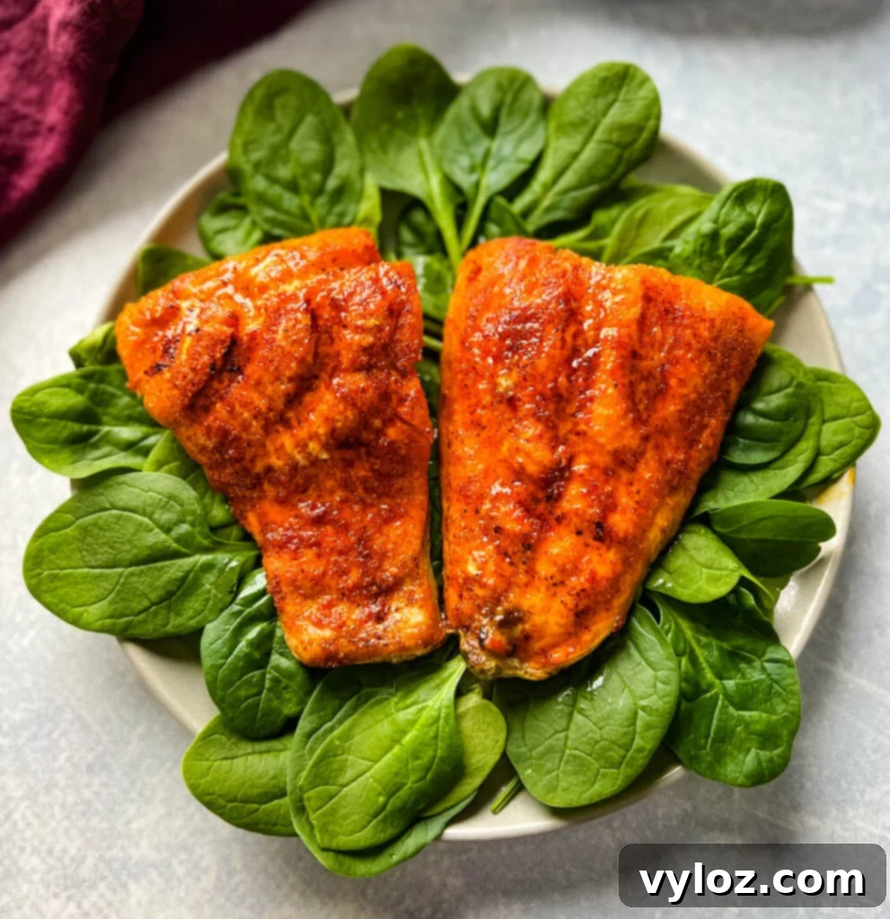 Ninja Foodi Grilled Salmon 9 Cooked indoor grilled salmon on a plate with fresh spinach and a lemon wedge.