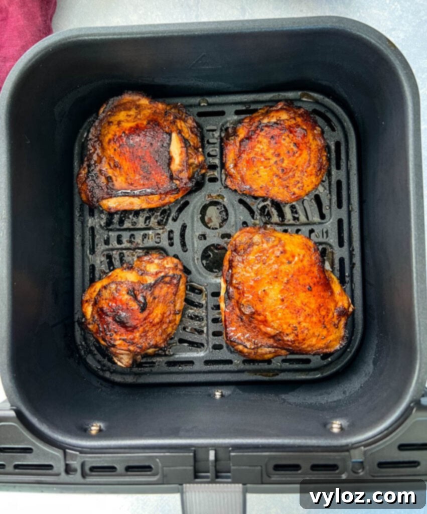 Jerk chicken thighs arranged neatly in an air fryer basket, ready for cooking.