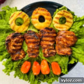 Jamaican jerk chicken thighs on a plate with peppers and grilled pineapples