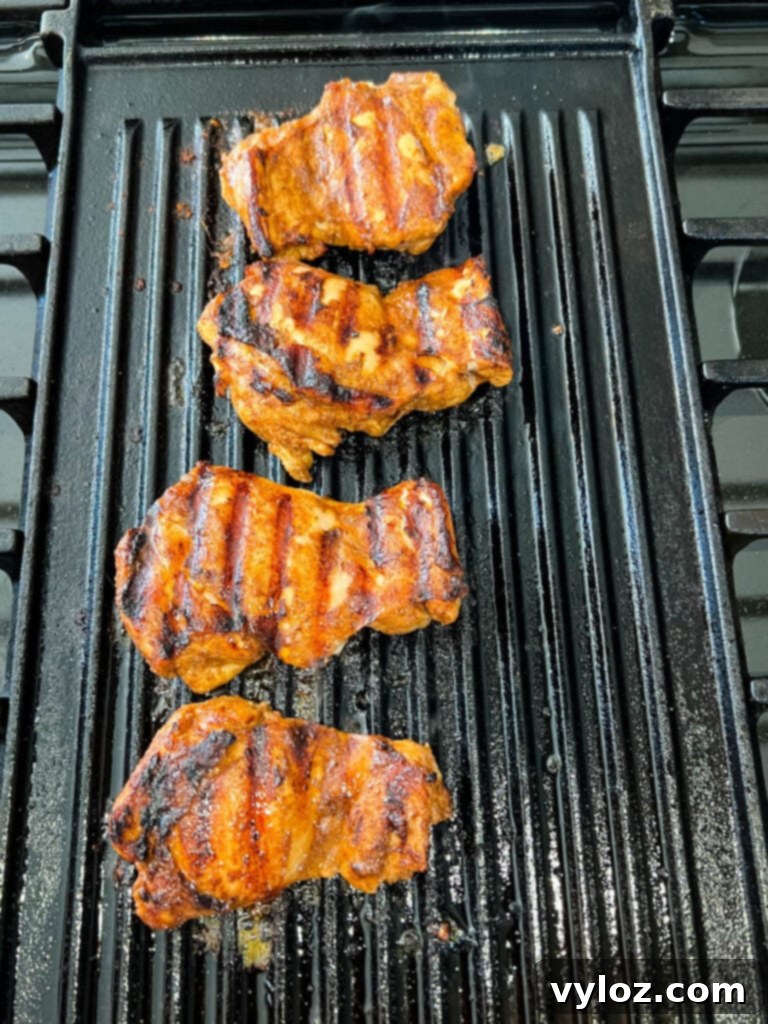 Cooked jerk chicken thighs beautifully charred on a grill pan, showcasing their crispy skin.