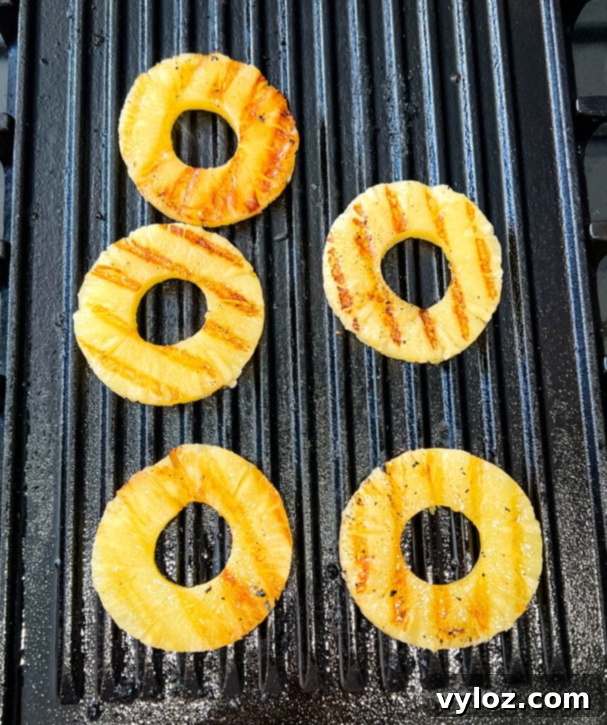Slices of grilled pineapple on a grill pan, ready to serve alongside jerk chicken.