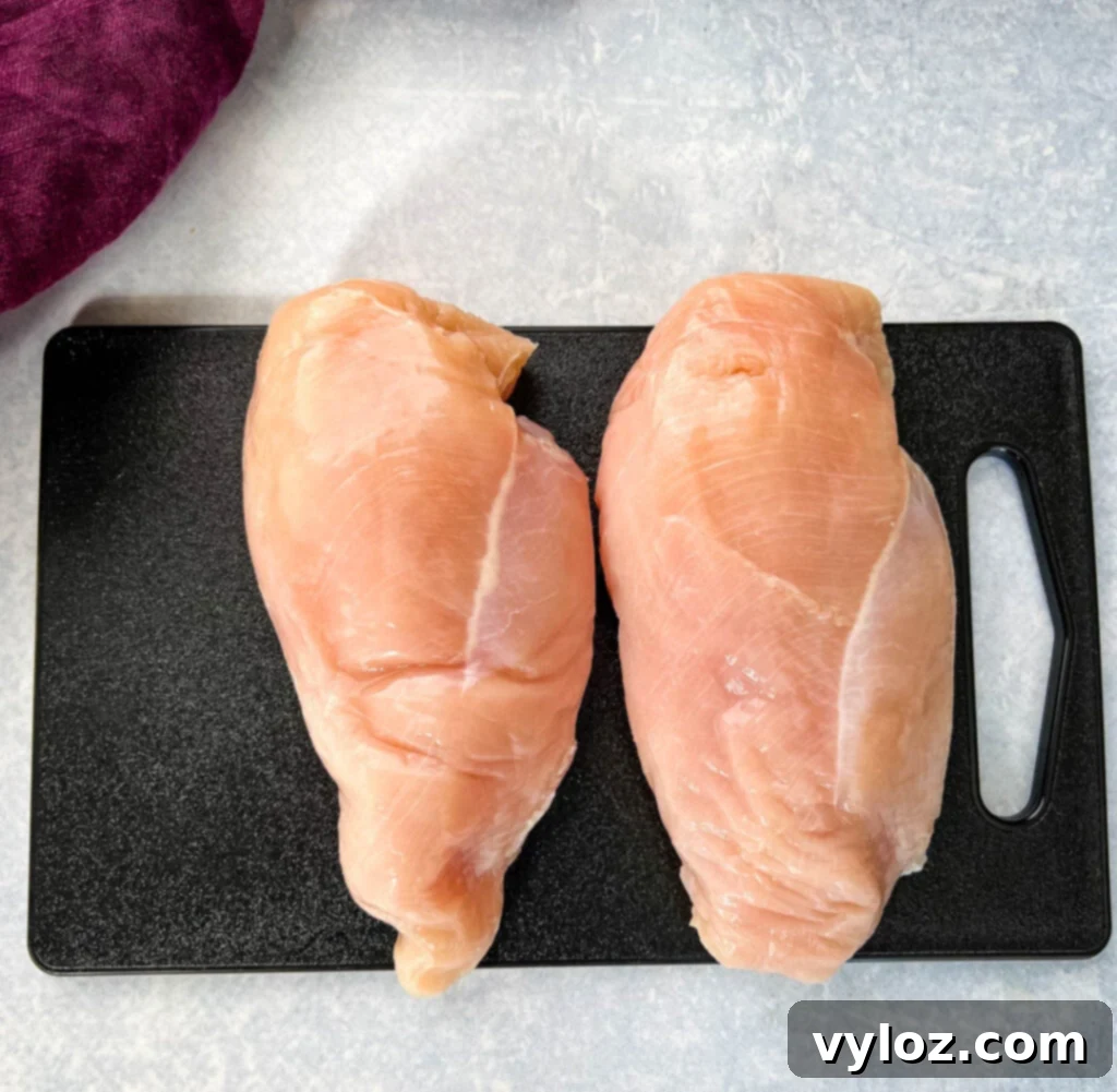 Raw chicken breasts on a wooden cutting board, ready for seasoning