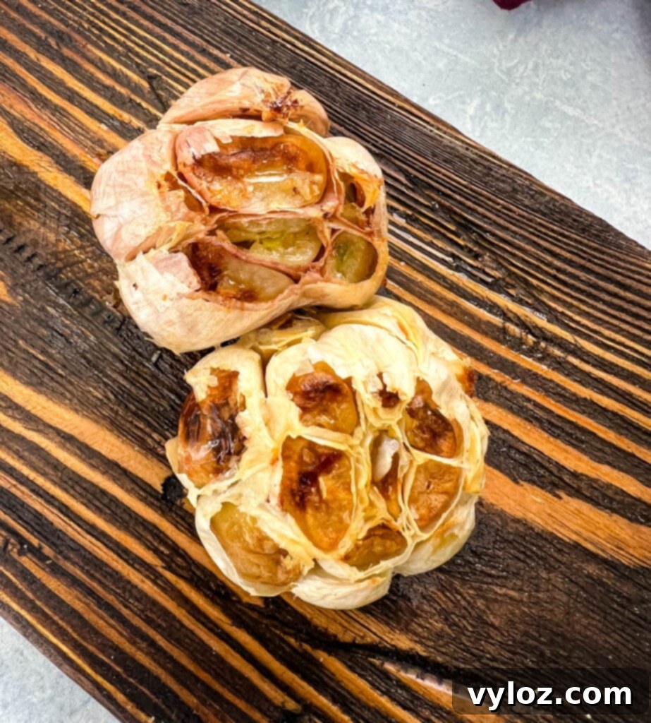 Caramelized Garlic Brussels Sprouts 5 Soft roasted garlic cloves on a small wooden plate