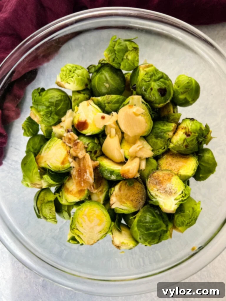 Caramelized Garlic Brussels Sprouts 6 Fresh, raw Brussels sprouts in a glass bowl with garlic and balsamic vinegar, ready to be tossed