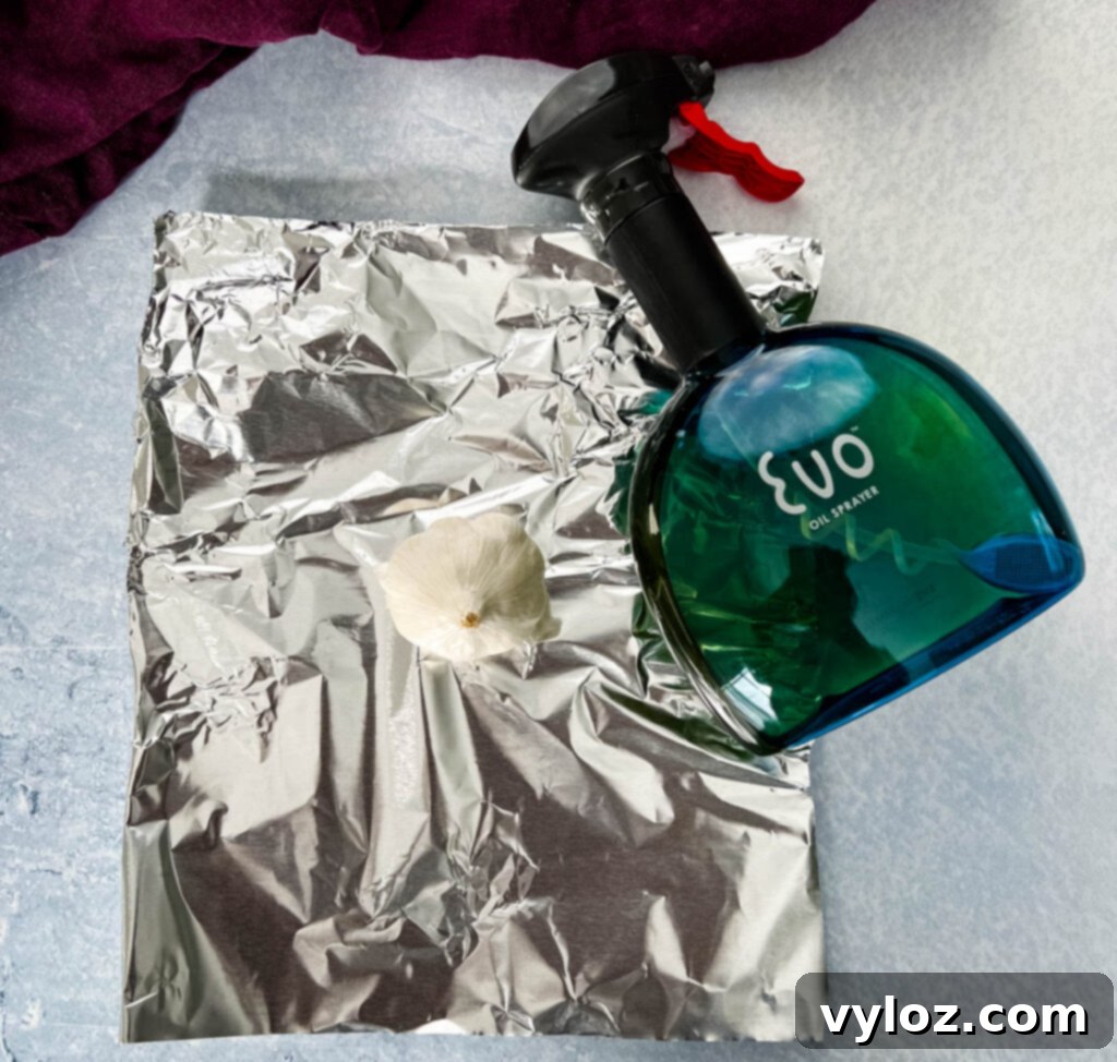 fresh garlic on foil with a bottle of olive oil