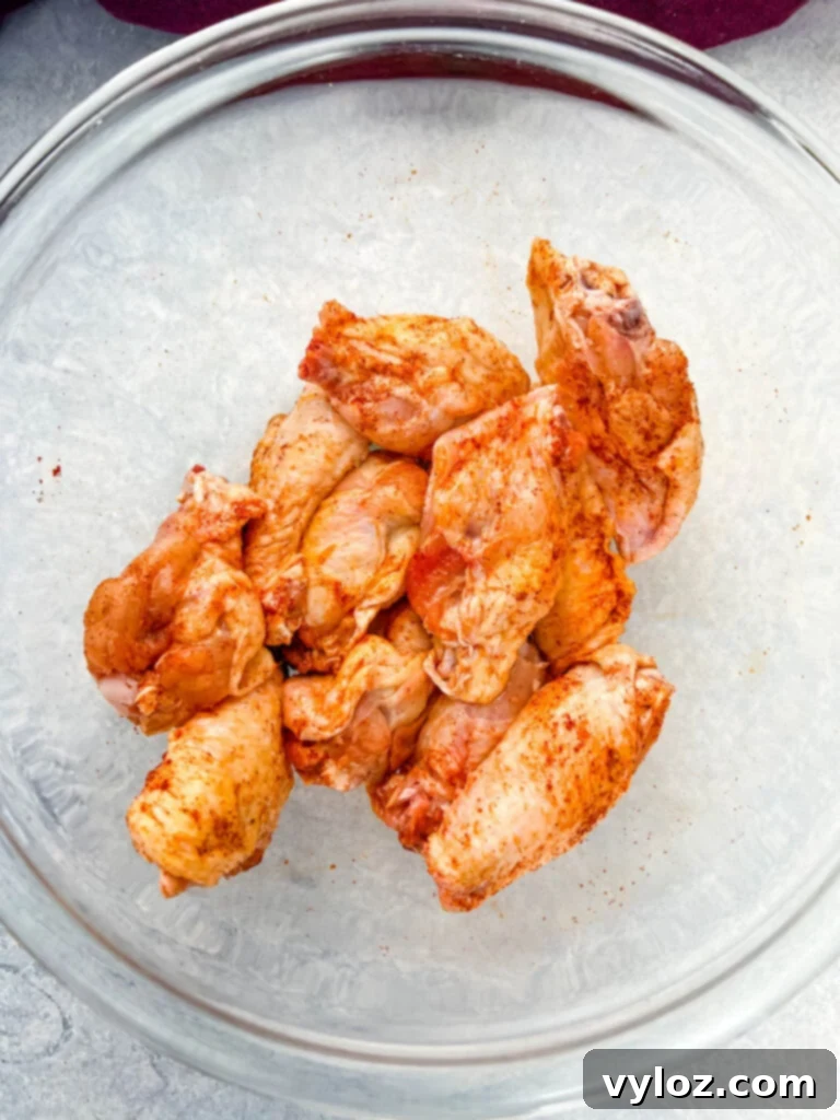 Close-up of raw chicken wings in a glass bowl, showcasing the ideal size for grilling.