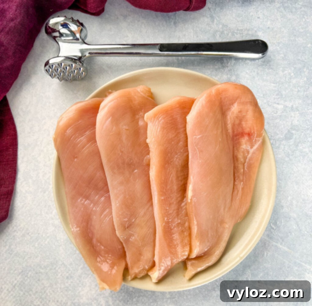 raw chicken breast cutlets on a plate with a mallet