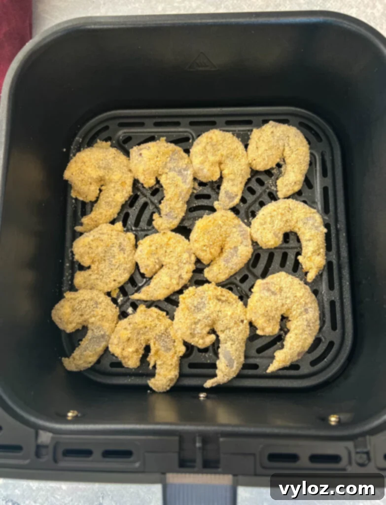 Breaded shrimp cooking in an air fryer for a crispy finish.
