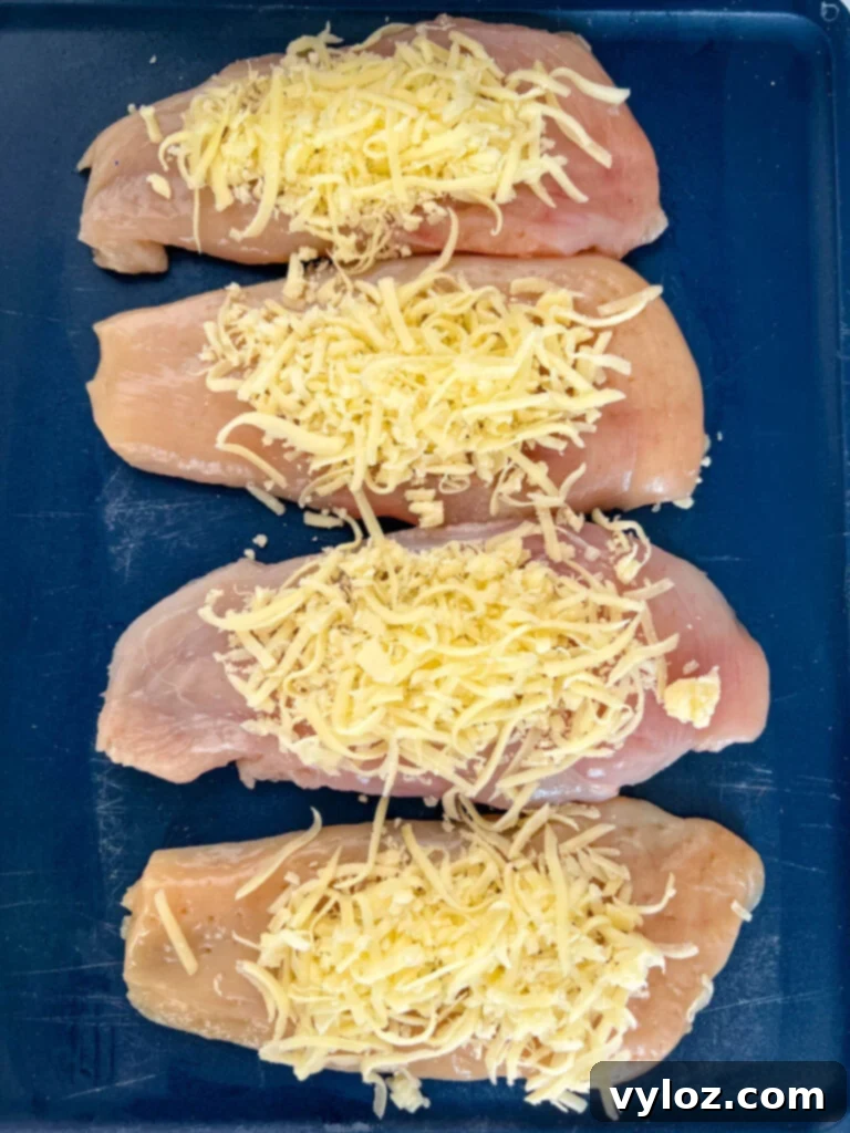 raw chicken breasts on a cutting board topped with mozzarella cheese