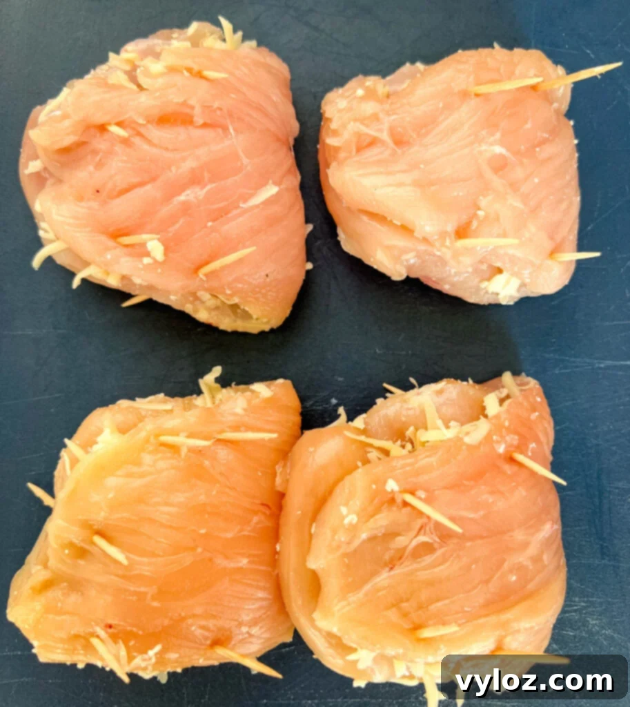 uncooked breaded stuffed mozzarella chicken breast on a cutting board