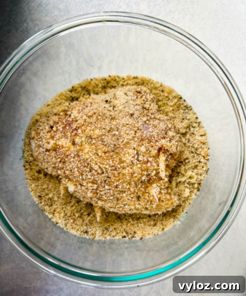 uncooked mozzarella stuffed chicken breast in a glass bowl with breadcrumbs