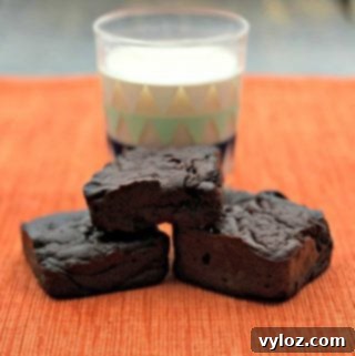 Three healthy brownies stacked in front of a glass of milk