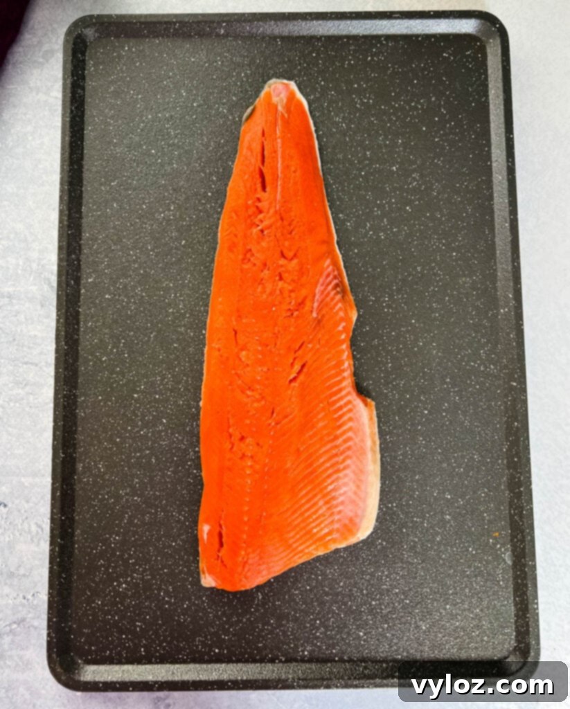 Ultimate Traeger Smoked Salmon 3 Raw, vibrant wild-caught salmon fillet on a sheet pan, ready for seasoning.