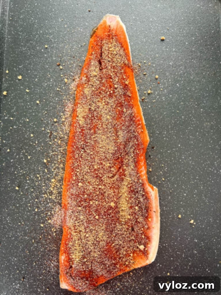 Ultimate Traeger Smoked Salmon 4 Raw wild-caught salmon fillet generously seasoned with a homemade BBQ rub on a sheet pan.