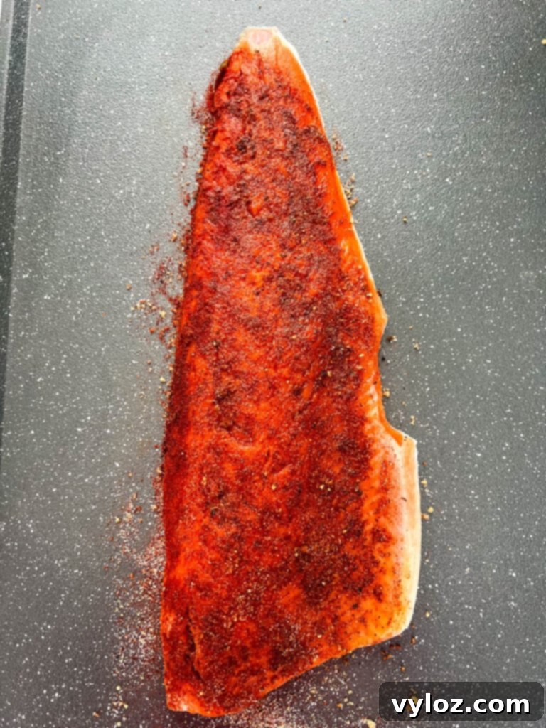 Ultimate Traeger Smoked Salmon 5 Close-up of raw wild-caught salmon fillet on a sheet pan, showcasing the even application of the homemade seasoning rub.