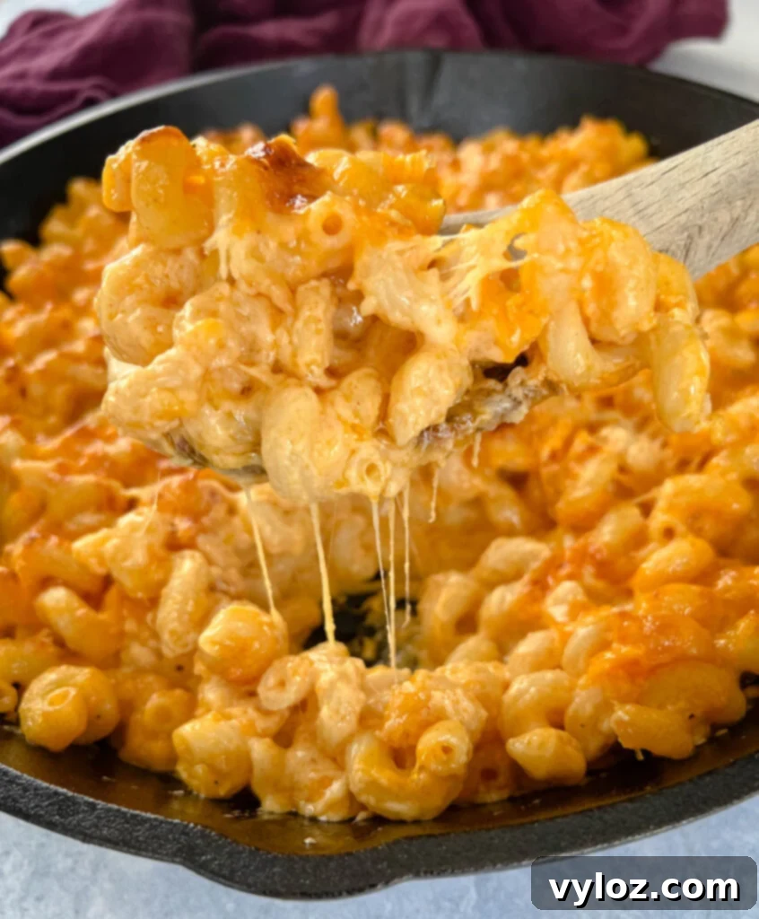 a wooden spoonful of smoked mac and cheese in a cast iron skillet