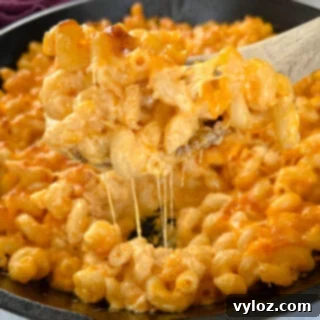 a wooden spoonful of smoked mac and cheese in a cast iron skillet