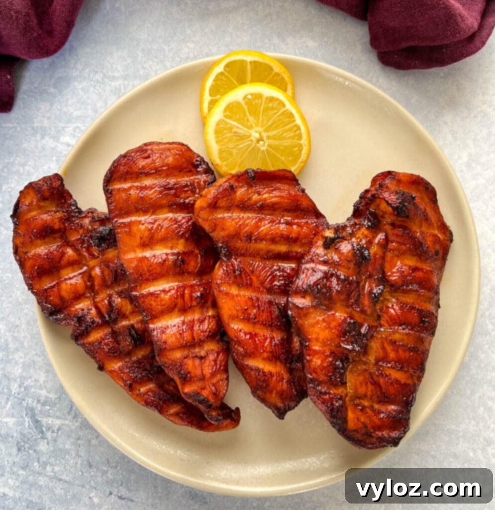 Traeger smoked chicken breasts on a plate with lemons, ready to serve.
