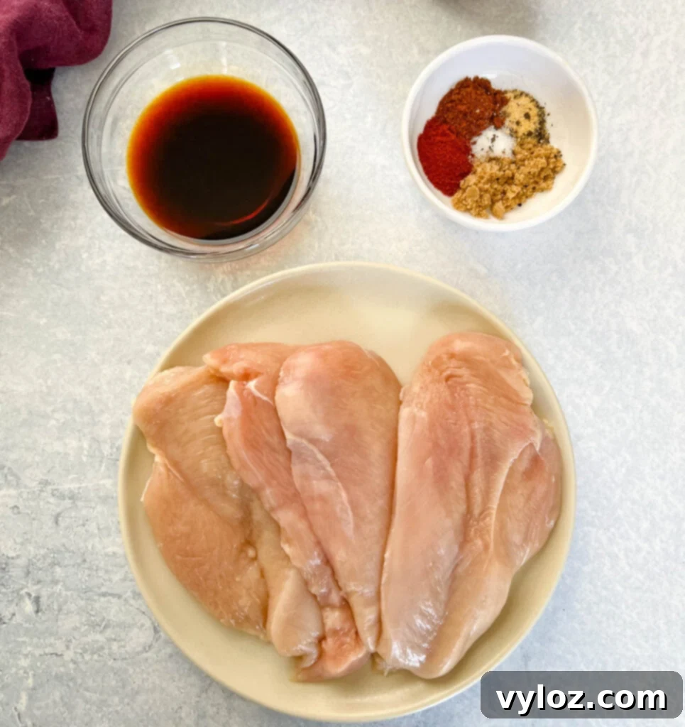 Raw chicken breasts, ready for seasoning, displayed with small bowls of soy sauce and spices.