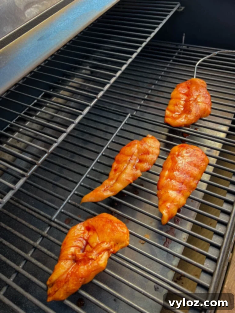 Raw chicken breasts arranged neatly on a Traeger smoker grill, ready for smoking.