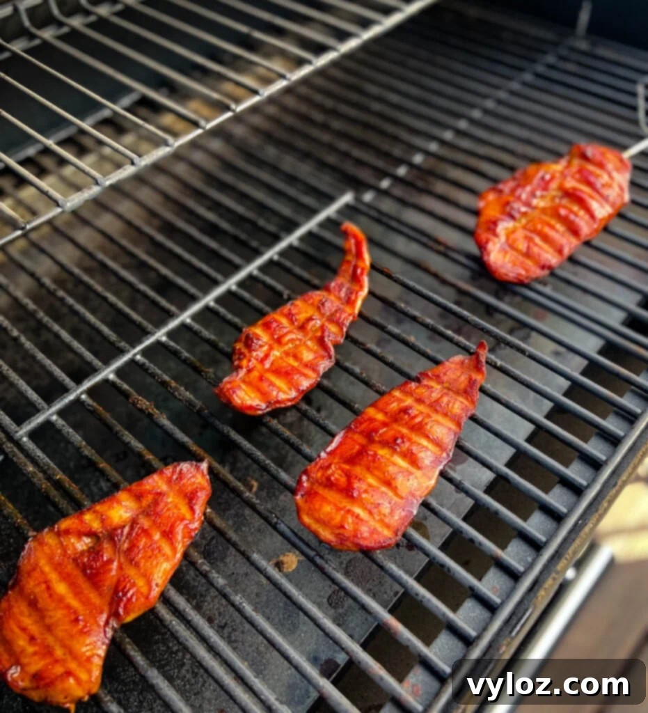 Perfectly smoked chicken breasts on a Traeger grill, with a temperature probe still in place.