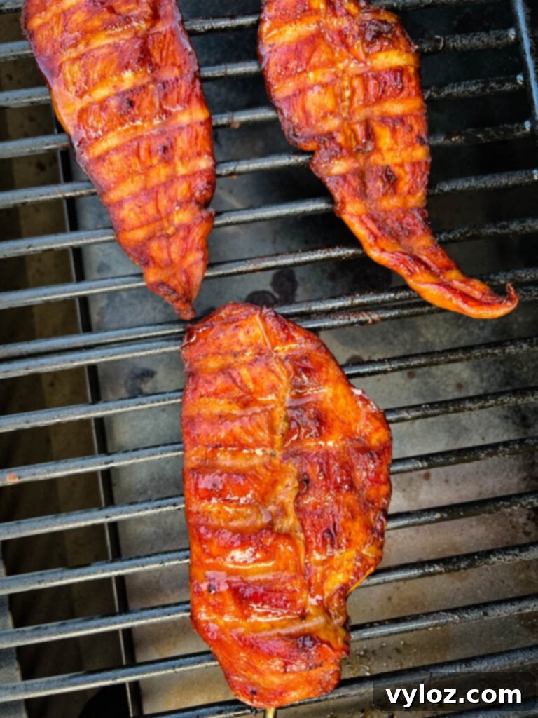Smoked chicken breasts resting on a Traeger grill after cooking.