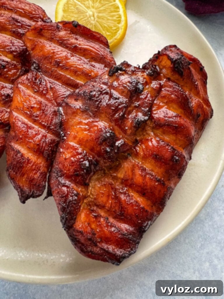 Plated Traeger smoked chicken breasts, garnished with fresh lemon slices, ready to eat.