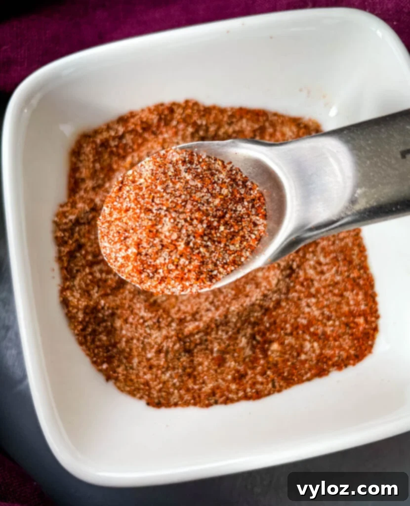 spices for chicken dry rub in a white bowl with a spoon