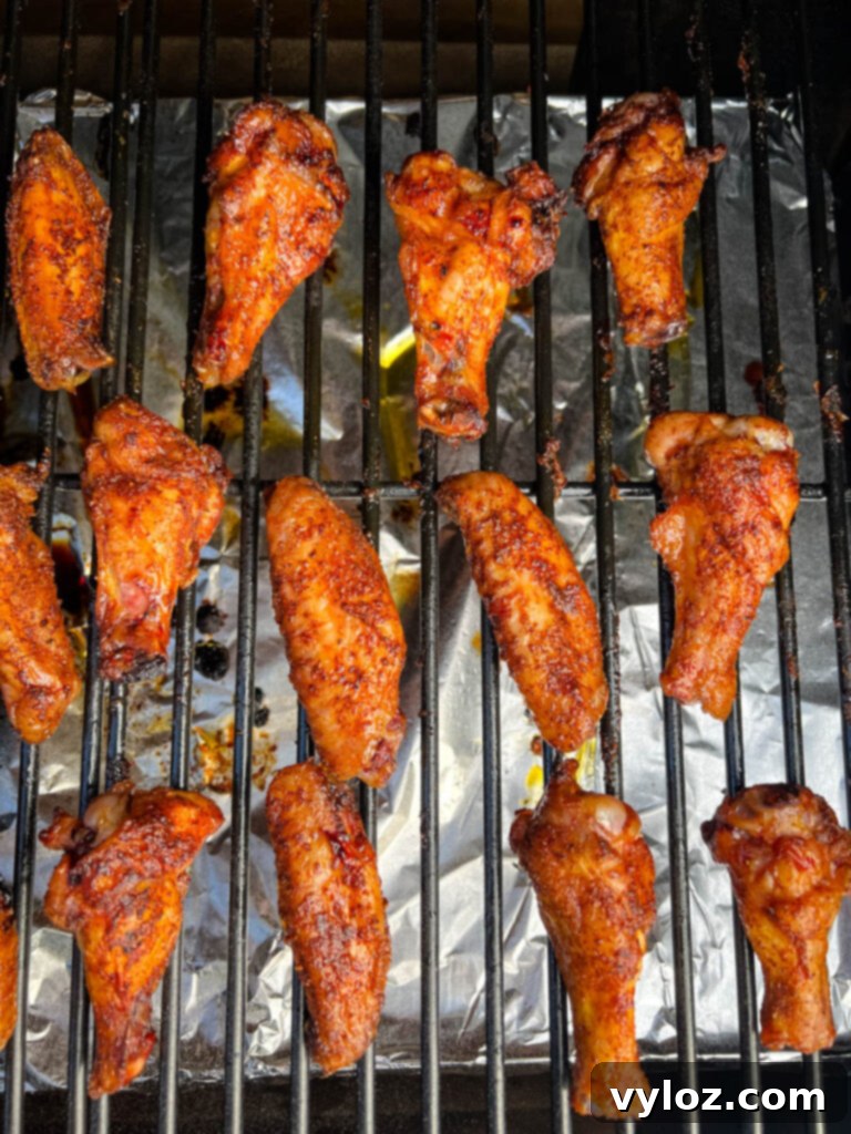 Cooked chicken wings resting on the grates of a Traeger smoker pellet grill, showcasing a delicious smoked exterior