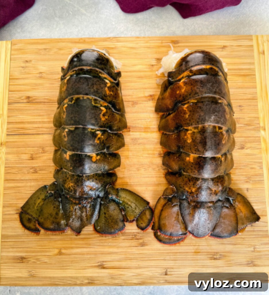 Effortless Smoked Lobster Tails 3 Raw lobster tails, pristine and ready for preparation, displayed on a clean cutting board.