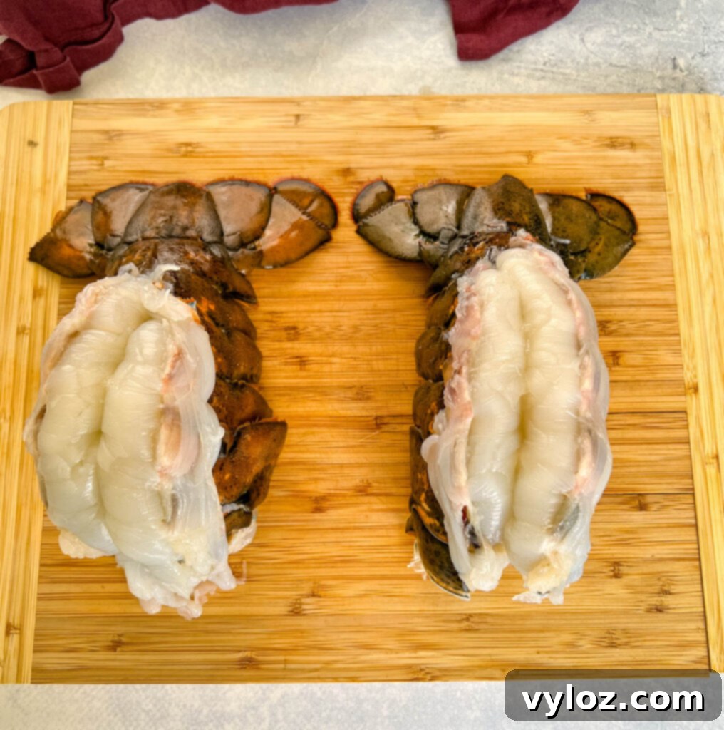 Effortless Smoked Lobster Tails 6 A raw butterflied lobster tail on a cutting board, with the shell expertly cut down the center.