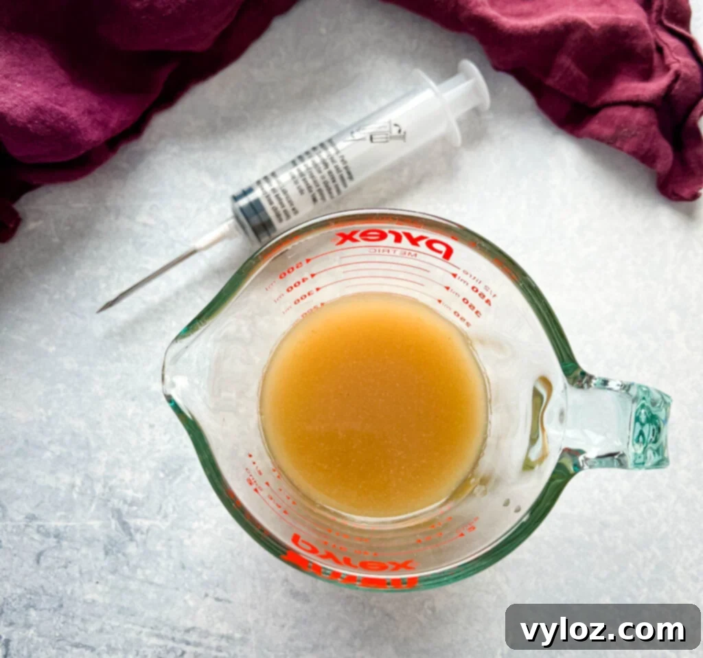 Juicy Traeger Smoked Turkey Breast 5 A glass cup holding a rich butter marinade injection, ready to be infused into the turkey for ultimate juiciness.