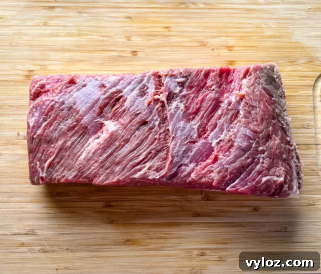 Raw beef brisket prepared for smoking on a bamboo cutting board, showing its generous marbling and texture.