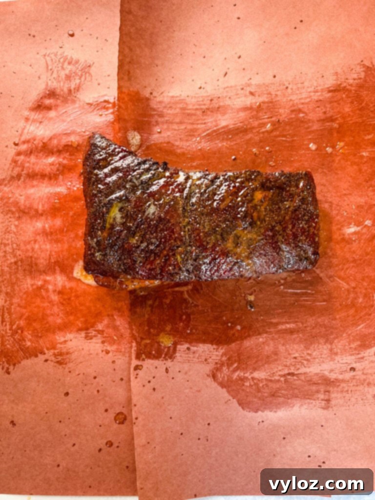 Traeger smoked brisket wrapped tightly in butcher paper, resting on the grill to finish cooking.