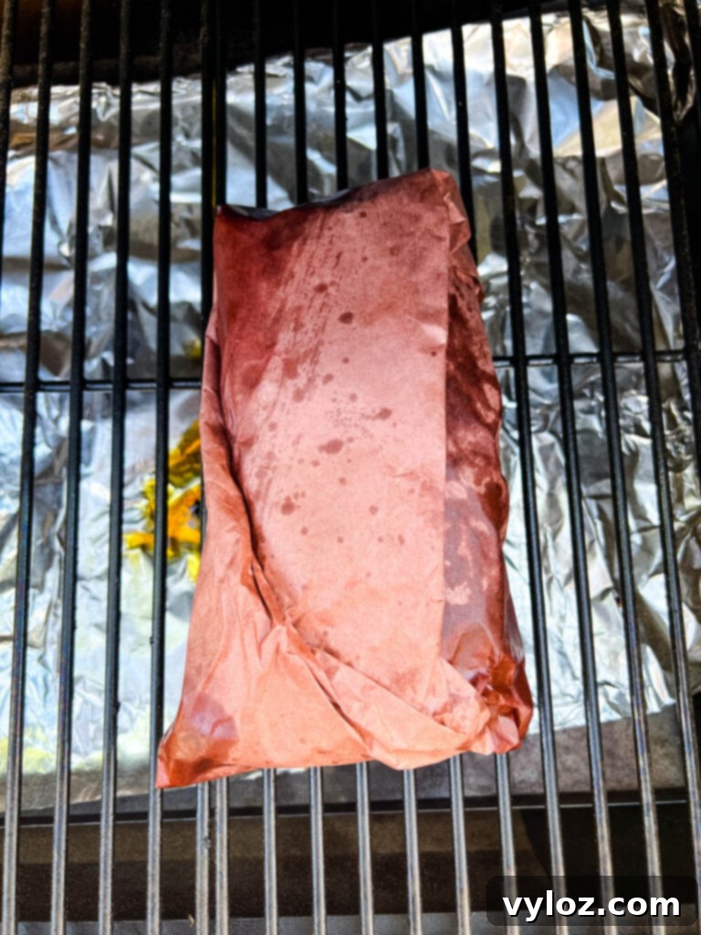 Traeger smoked brisket, perfectly wrapped in butcher paper, continuing its slow cook on the pellet grill.