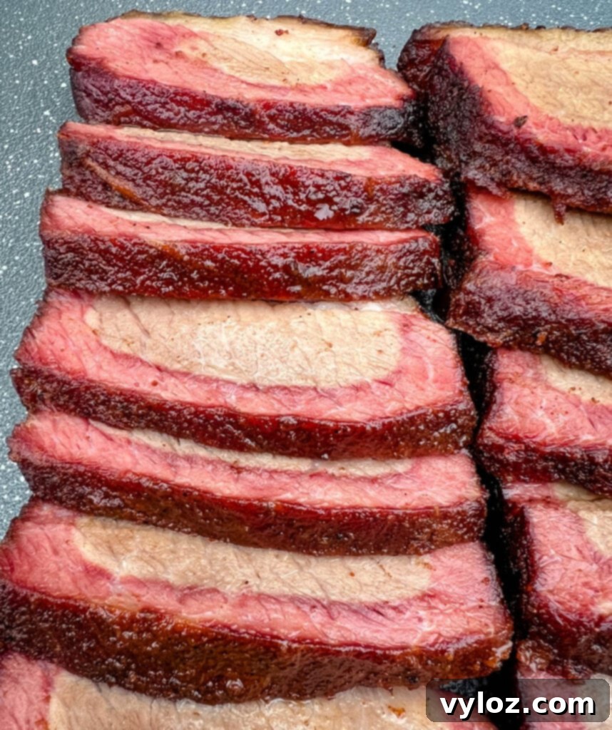 Traeger smoked brisket, sliced and arranged on a white plate, showcasing its tender texture.