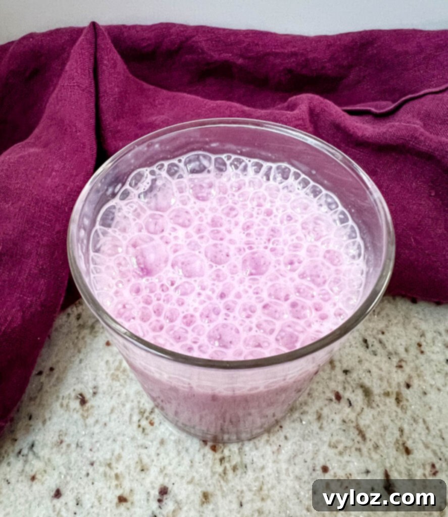 A close-up of a glass of Angel Milk, showcasing its frothy top and the soft color, ready to be enjoyed.