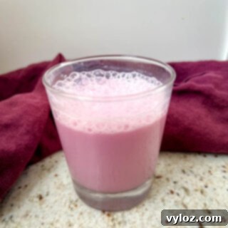 A beautifully presented glass of Angel Milk with a pink hue and frothy top.