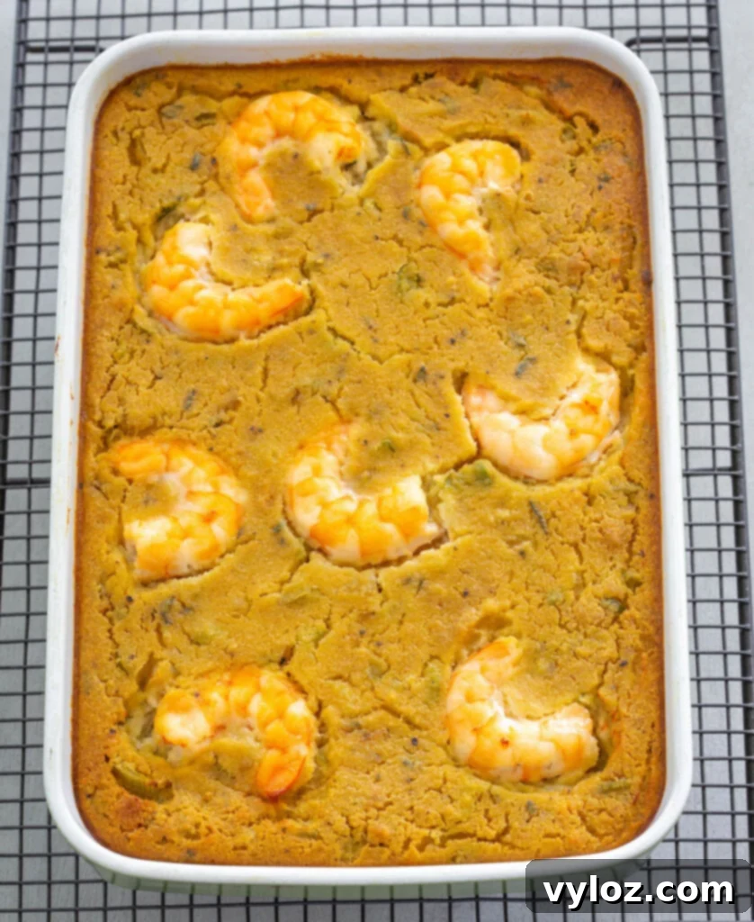 The Ultimate Seafood Dressing 9 Freshly baked seafood cornbread dressing with shrimp and a golden crust, cooling in a baking dish.