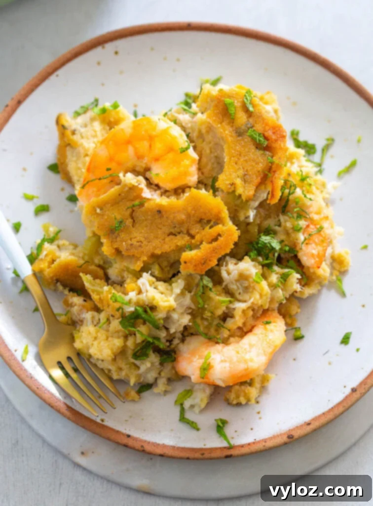 The Ultimate Seafood Dressing 10 A serving of seafood cornbread dressing, showcasing its rich texture and flavorful ingredients, on a white plate.