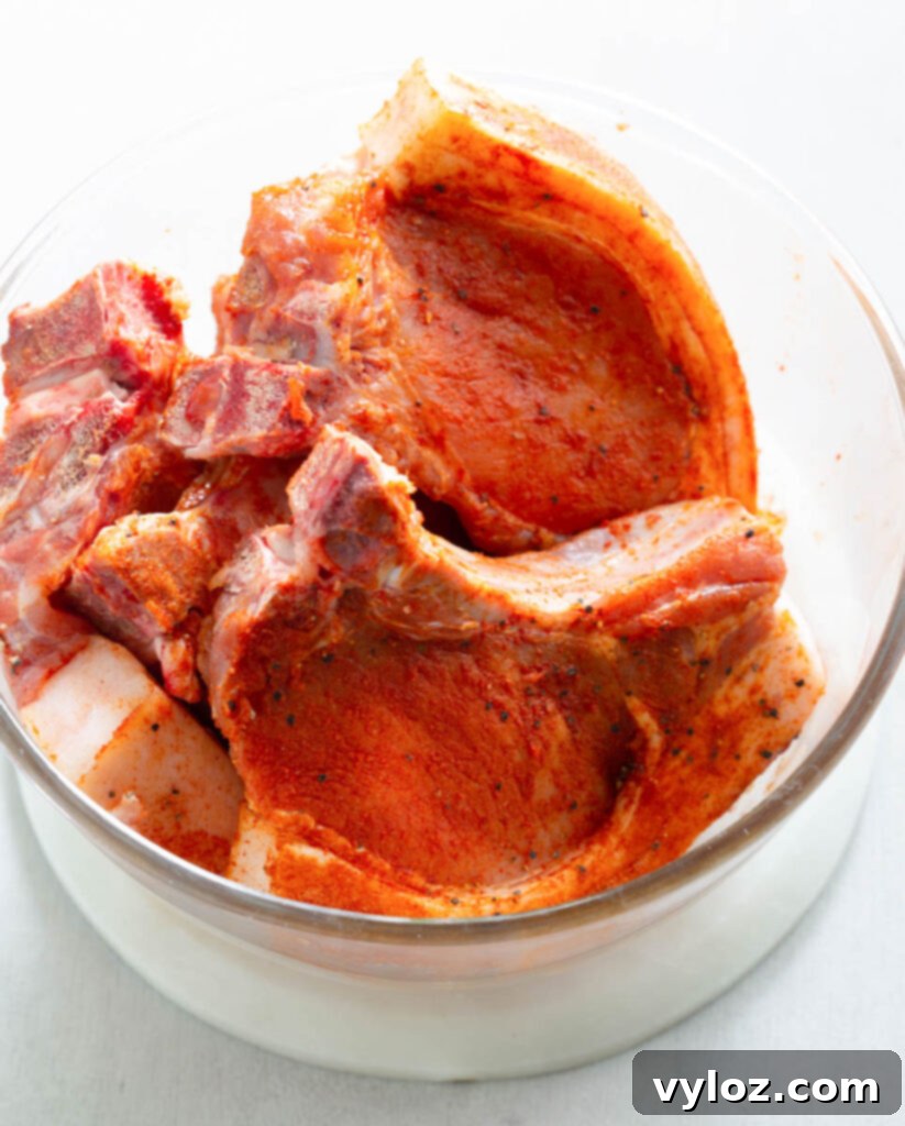 Soulful Southern Smothered Pork Chops 4 raw seasoned pork chops in a glass bowl