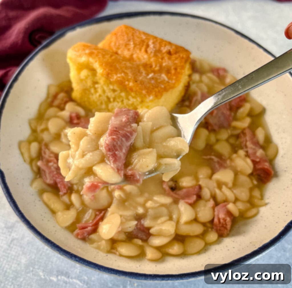 A bowl of Southern butter lima beans served with a side of golden cornbread, a classic comforting meal.