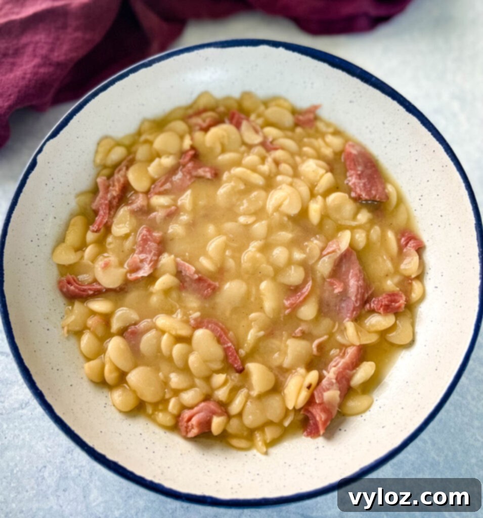 A spoonful of creamy Southern butter lima beans, scooped into a white bowl, showcasing their rich texture.