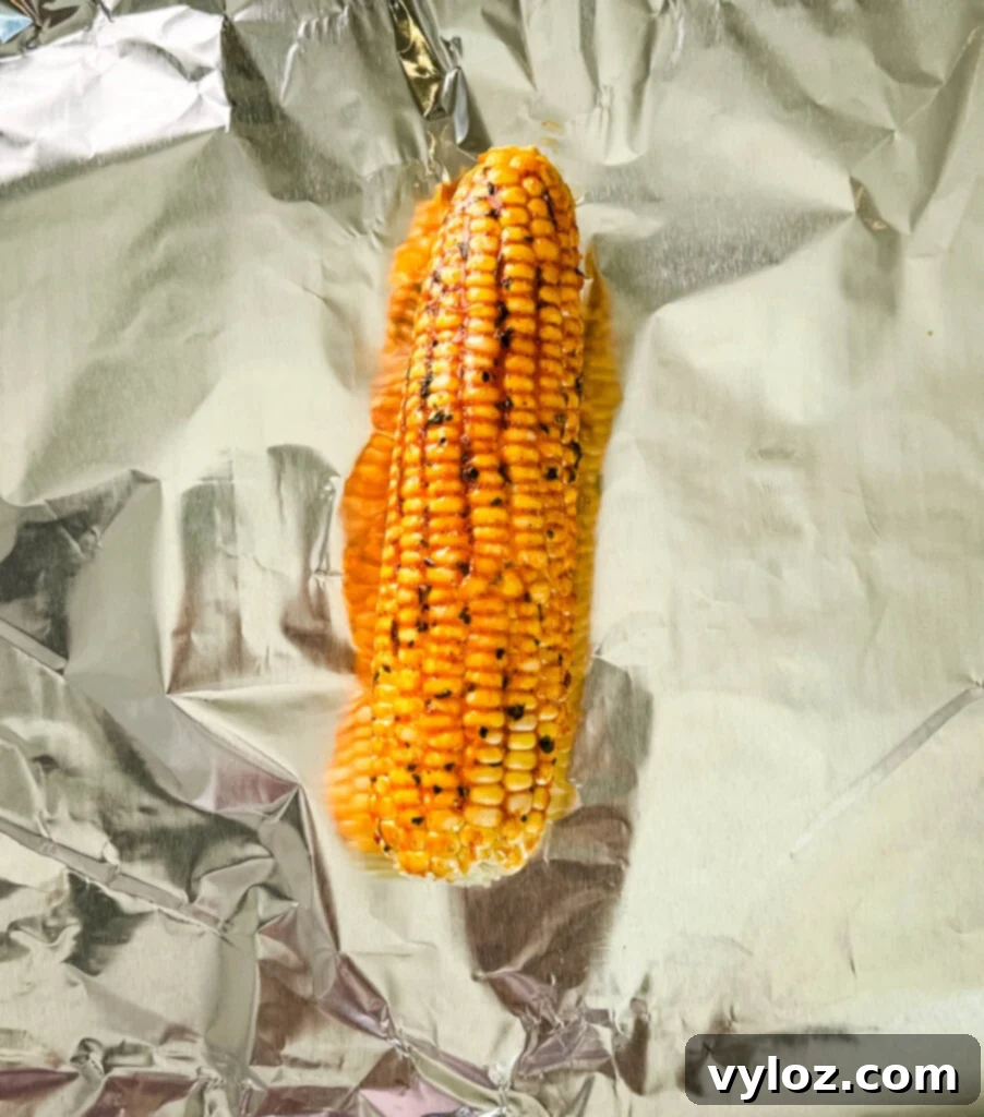 Seasoned corn on the cob on foil, ready for wrapping