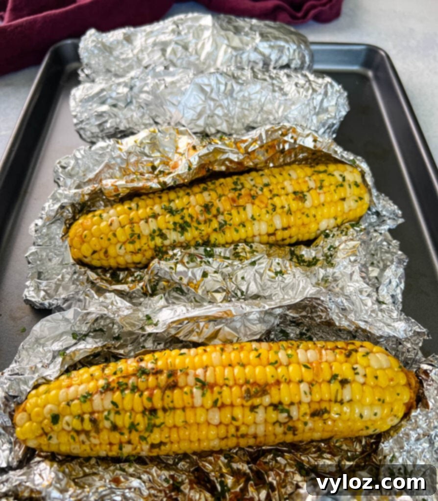 Freshly baked oven roasted corn on the cob in foil, hot and steamy