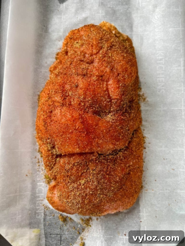 Raw boneless turkey breast generously seasoned with herbs and spices, ready for slow cooking