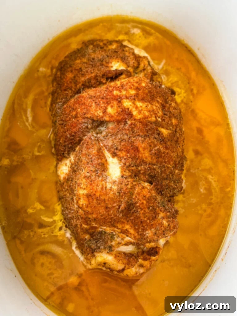 Sliced boneless turkey breast resting in a slow cooker, showcasing its tenderness and juiciness