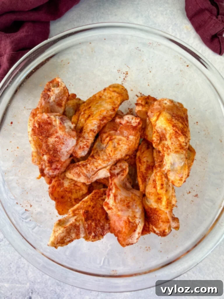 Savory Smothered Chicken Wings 3 raw seasoned chicken wings in a glass bowl